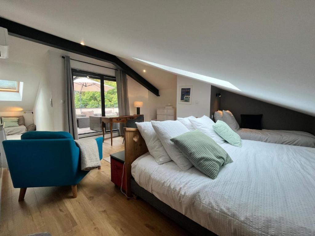 une chambre avec un grand lit et une chaise bleue dans l'établissement La Dame du Lac à Sevrier, à Sévrier