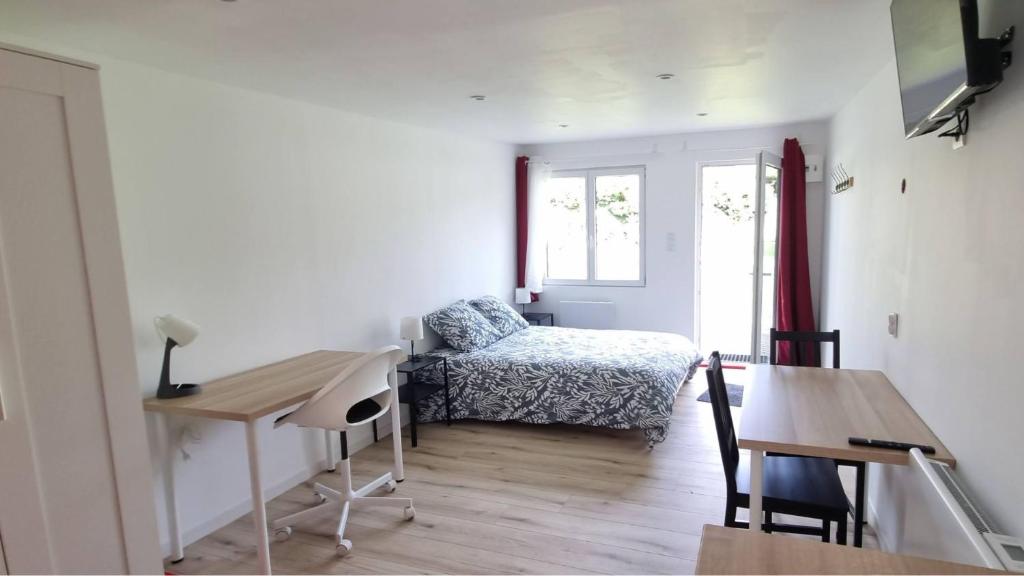 a room with a bed and a desk and a table at Le petit Château Avesnois - Studio avec terrasse vue sur le jardin in Avesnes-sur-Helpe
