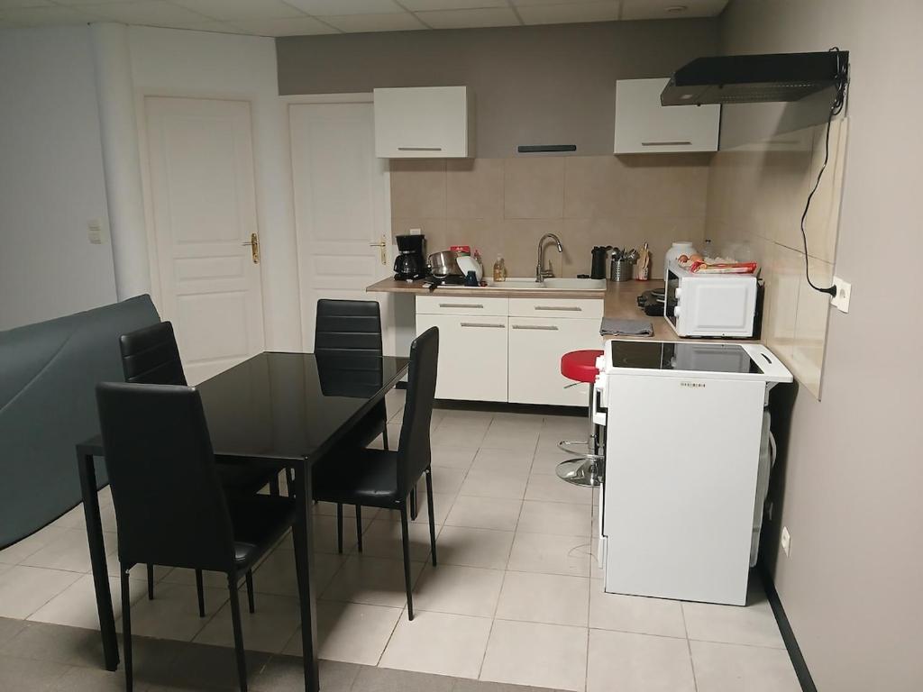 a kitchen with a table and chairs and a kitchen with white cabinets at Studio familial avec terrasse, proche de Metz in Rémilly