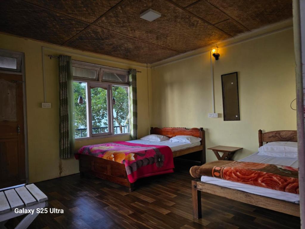 a bedroom with two beds and a window at Dara Homestay, Charkhole in Kalimpong