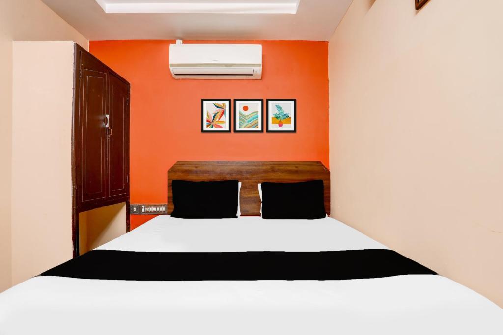 カルヌールにあるHotel O Woodlandsのオレンジ色の壁と白いベッドのある寝室