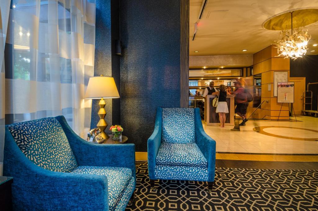 duas cadeiras azuis num átrio com pessoas no corredor em Beacon Hotel & Corporate Quarters em Washington