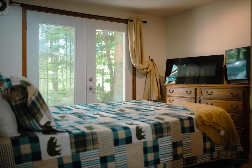 a bedroom with a bed and a dresser and a television at A New A-Frame of Mind Cabin in Birnamwood