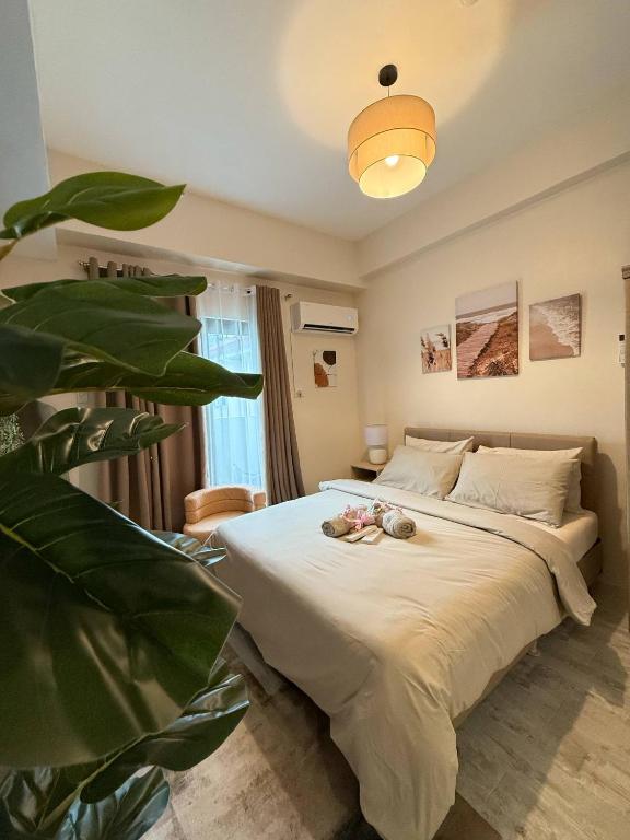 a bedroom with a large bed with a plant at Cozy 1BR in Zef, Near Anjo World Wifi, Pool, Gym in Minglanilla