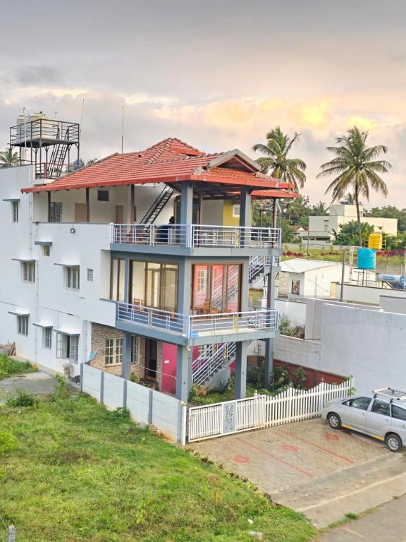 une maison blanche avec un toit rouge et une voiture dans l'établissement Evergreen Shola View, à Chikmagalur
