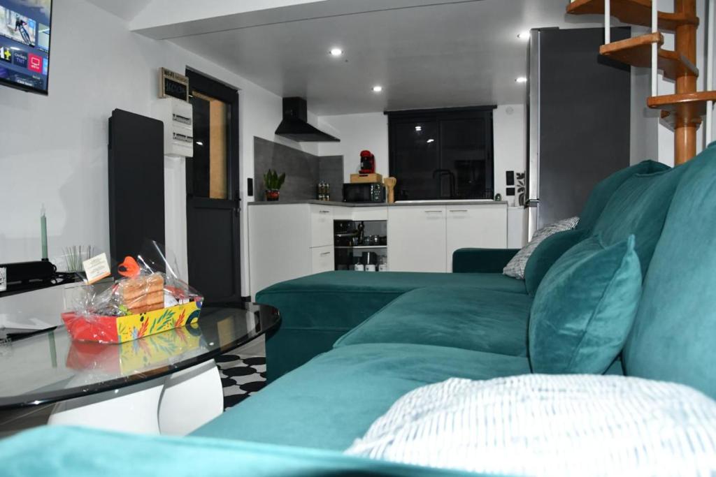 a living room with a green couch and a glass table at Eden House in Saint-Pierre-Canivet