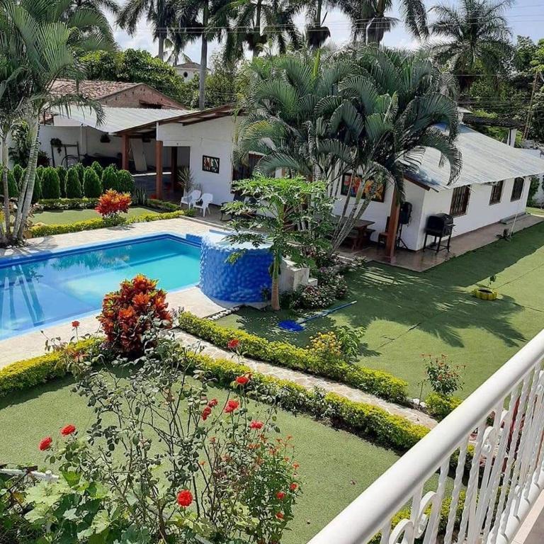 Un patio trasero con piscina y una casa. en Casa Campestre VILLA LOLITA, en Rozo
