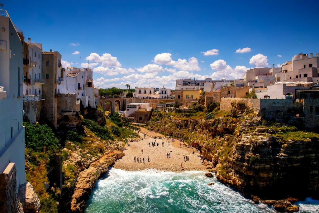 un gruppo di persone in piedi su una spiaggia vicino all'oceano di La Steila del Sud a Polignano a Mare