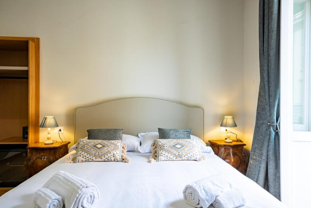 a bedroom with a large white bed with two lamps at MAMA Relais in Rome