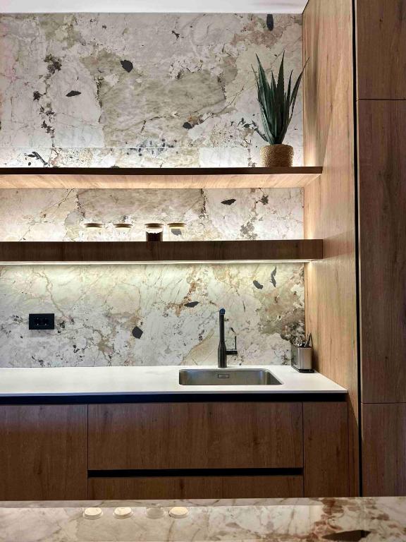 a kitchen with a sink and a marble wall at Apartman A 07 u sklopu hotela Vučko in Jahorina