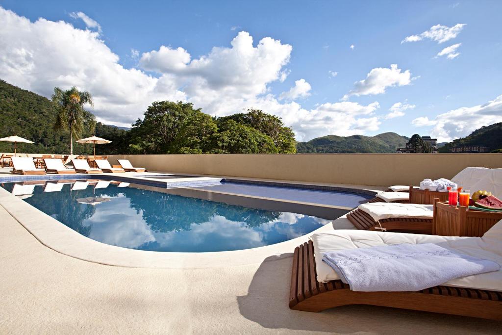 einen Pool mit Liegestühlen neben einem Resort in der Unterkunft Hotel Granja Brasil Resort in Itaipava
