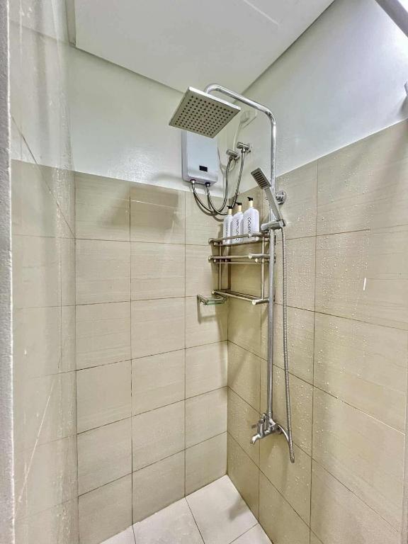 une douche avec pommeau de douche dans une salle de bain dans l'établissement Lanzon Azure Urban Resort Staycation, à Manille