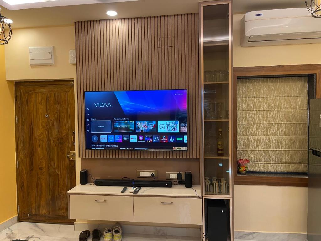 kolkataにあるJN 2BHK Studio Apartment Biratiの客室内の壁に大画面薄型テレビが備わります。