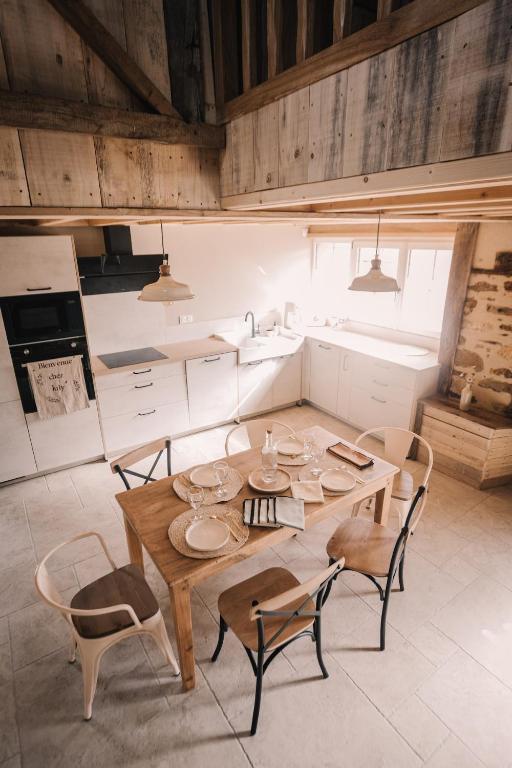 a kitchen with a wooden table and chairs at La maison de July in La Roë