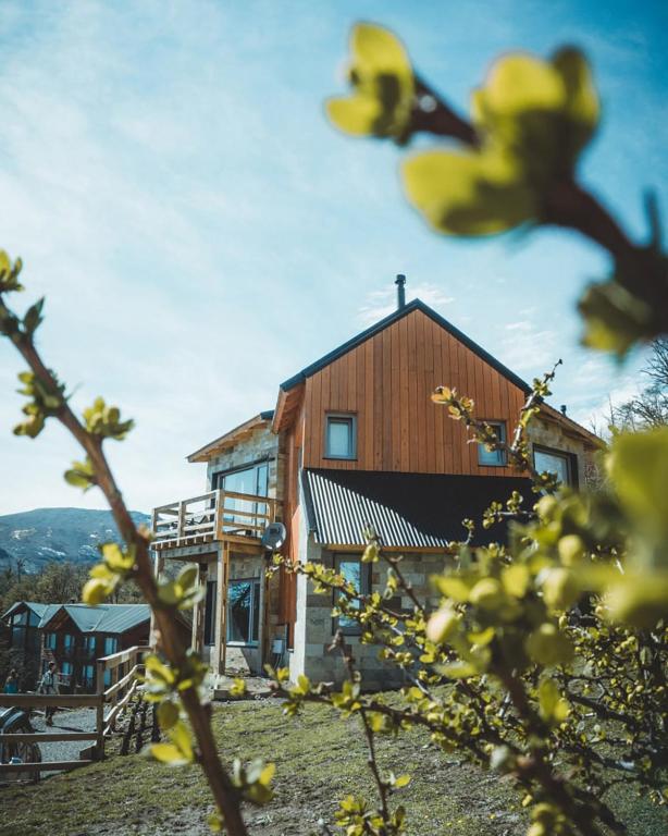 a wooden building with a house in the background at Bosque Nevado in San Martín de los Andes
