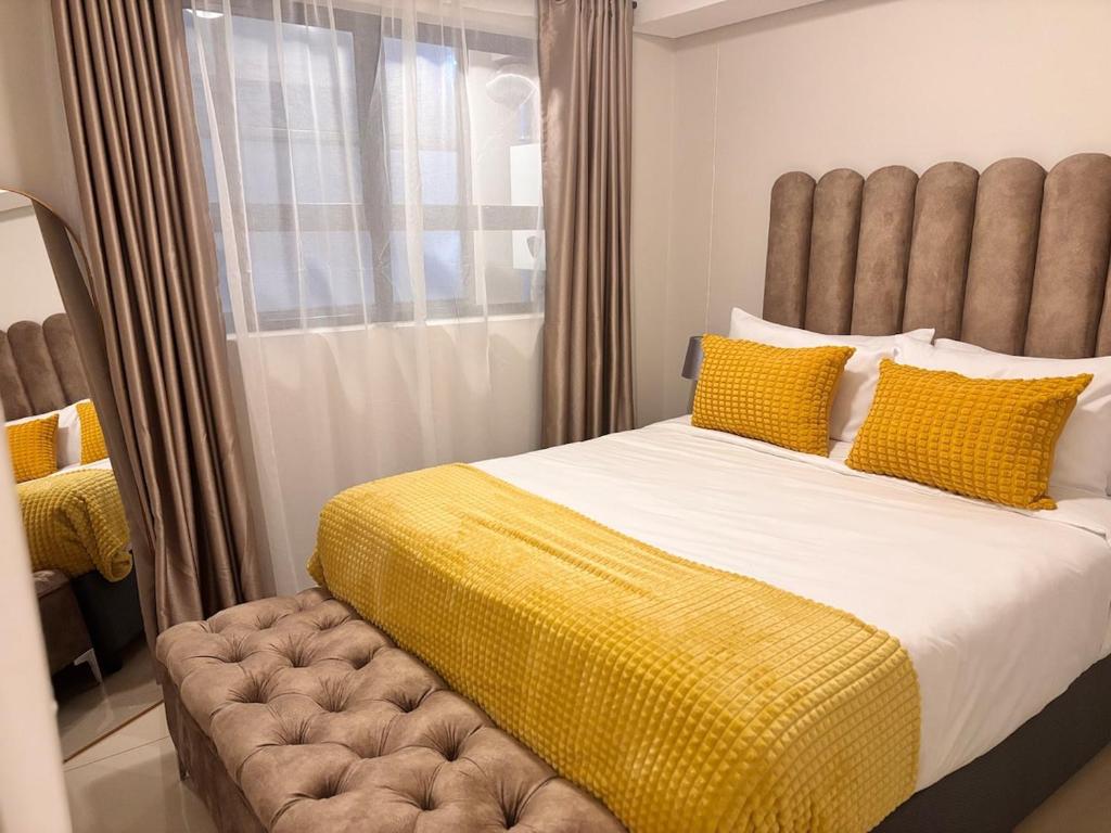 a bedroom with a large bed with yellow pillows at The Cozy Maldives in Durban