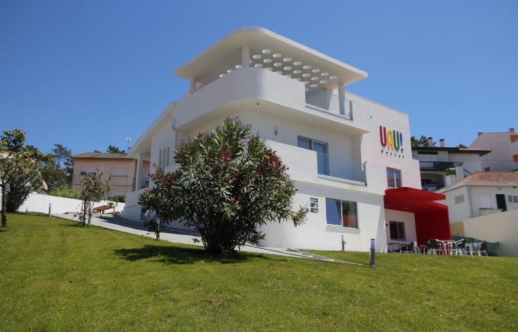 un edificio bianco con un albero di fronte di UAU Hostel a Figueira da Foz