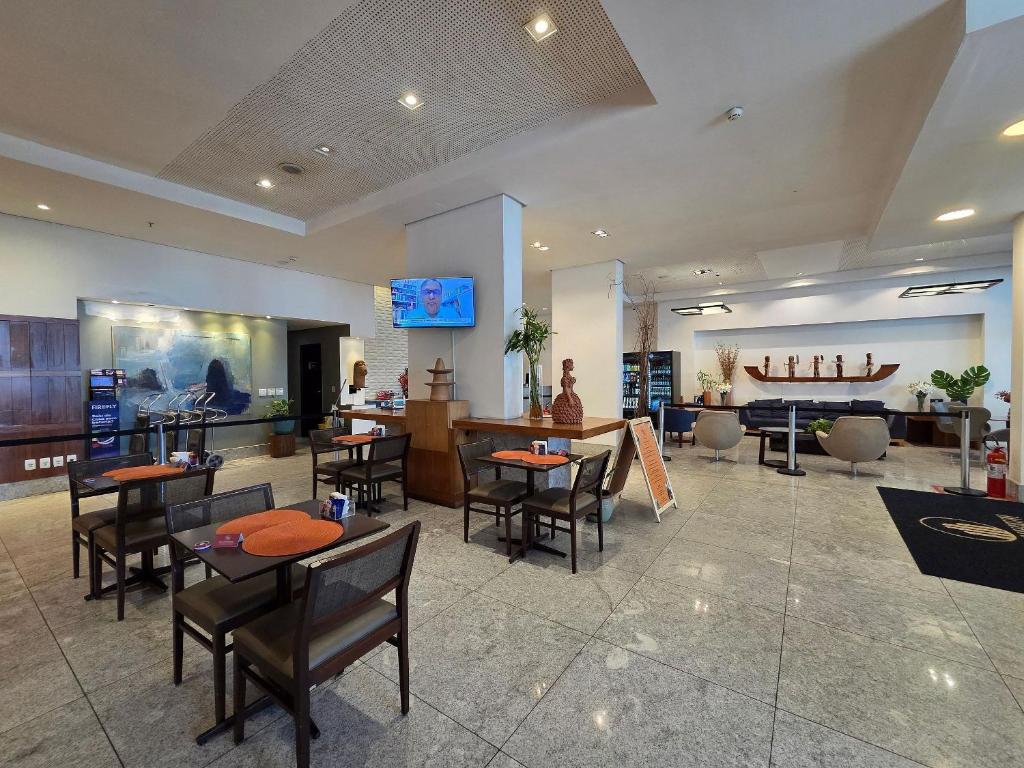 een restaurant met tafels en stoelen en een bar bij Beach Class Executive por Yolo in Recife