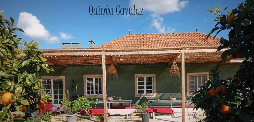 una casa verde con techo de paja en Quinta Cavaluz, en Poceirão
