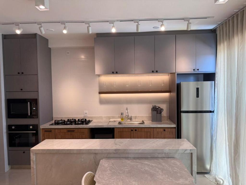 a kitchen with wooden cabinets and a stainless steel refrigerator at High standard apartment, well located in Anápolis