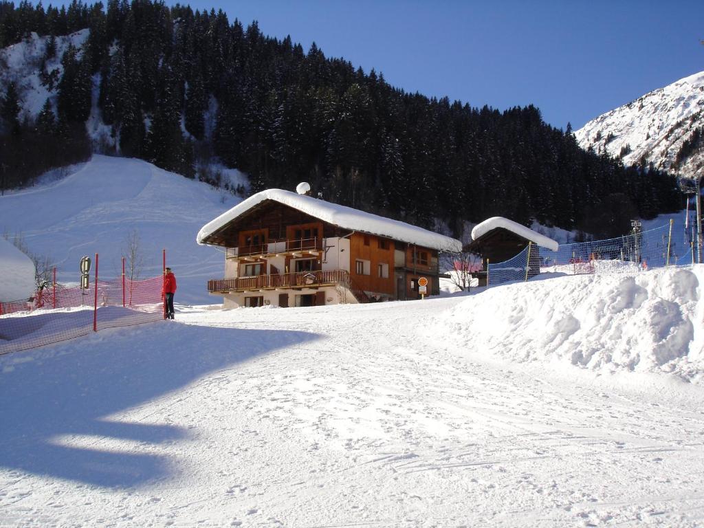 um homem parado em frente a um edifício na neve em Les Myosotis em Arêches