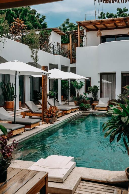 een zwembad bij een hotel met ligstoelen en parasols bij Casa Beu Hotel Boutique in Puerto Escondido