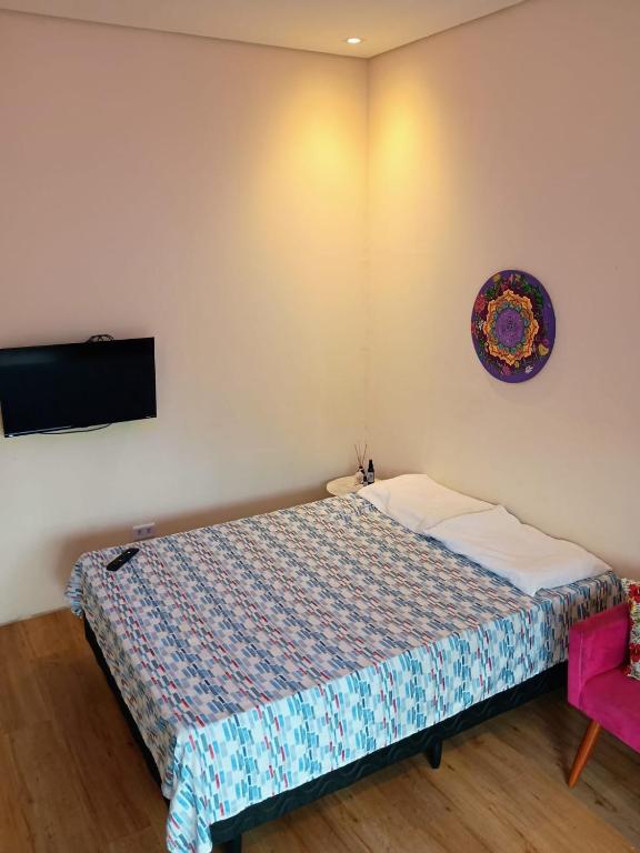 a bedroom with a bed and a tv on the wall at Quarto vista mar São Sebastião in São Sebastião