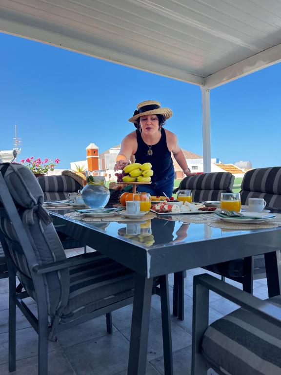 a woman standing at a table with fruit on it at Aloe Apartament 2 plus 1 gratis w Casa Verde de Guía in Santa Maria de Guia de Gran Canaria