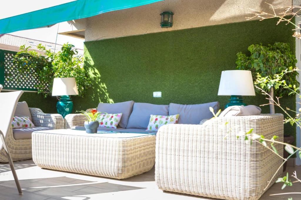 a patio with wicker furniture and a green wall at AMAZING ROOFTOP, 70 M TERRACE,Pool,BEACH,PARKING in Málaga