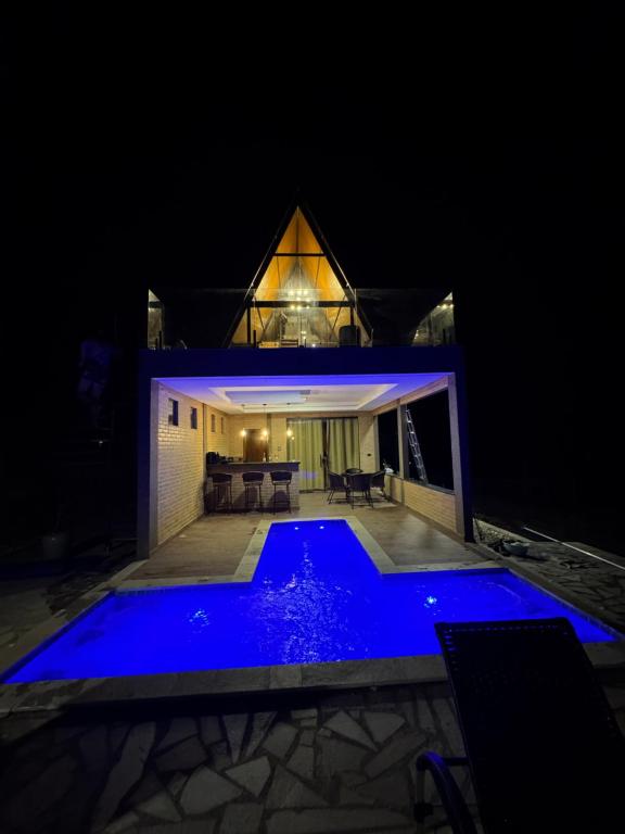 una casa con piscina azul por la noche en Chalé Ypê Amarelo Ypês da Serra, en Pirenópolis
