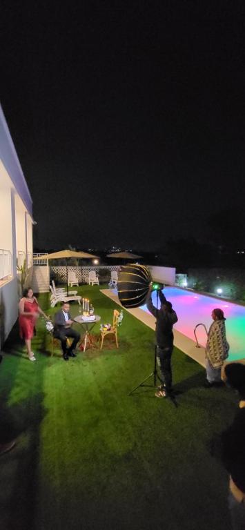 een groep mensen die 's nachts rond een zwembad staan bij Smile Apartments Arusha in Arusha