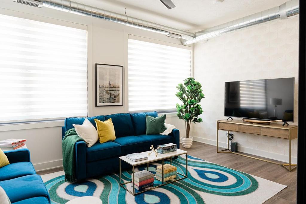 a living room with a blue couch and a tv at Husker Home TEN40 is in the heart of Downtown Lincoln where you can walk to Haymarket & UNL in Lincoln