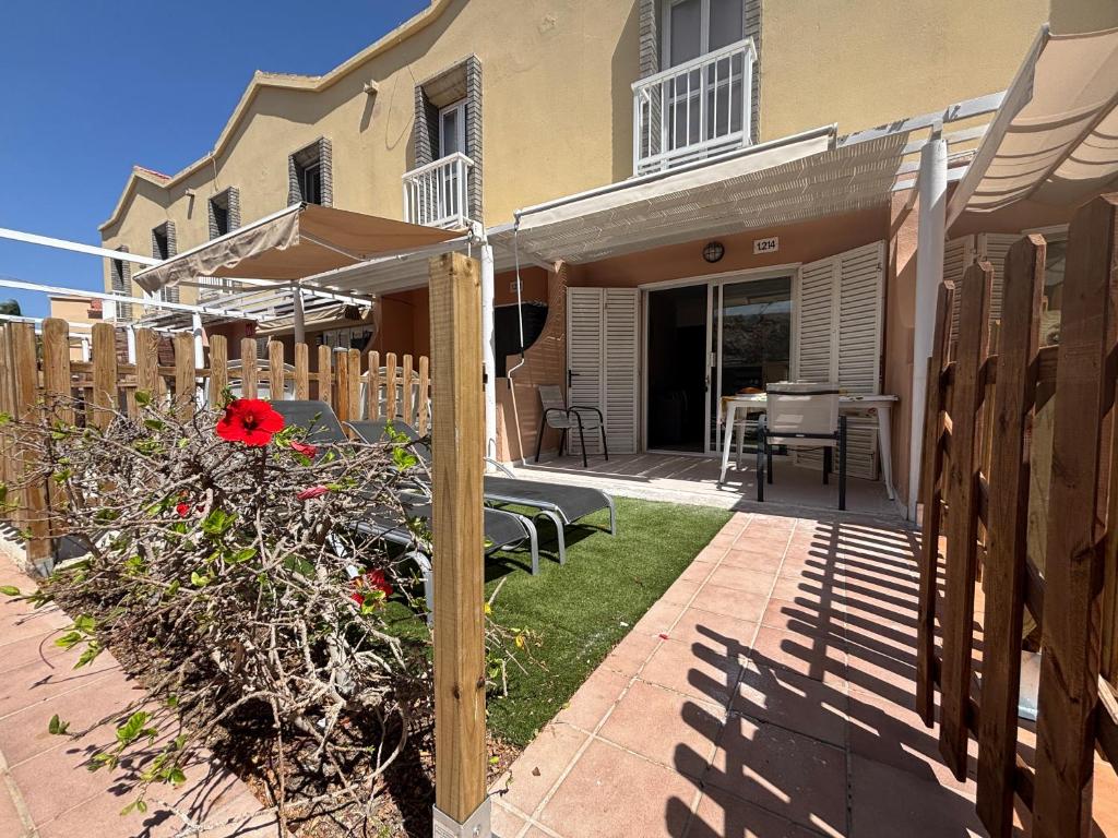 a house with a patio with a bench and an umbrella at Blu Green Oasis 1214 By Lucapropertiesgrancanaria in Maspalomas