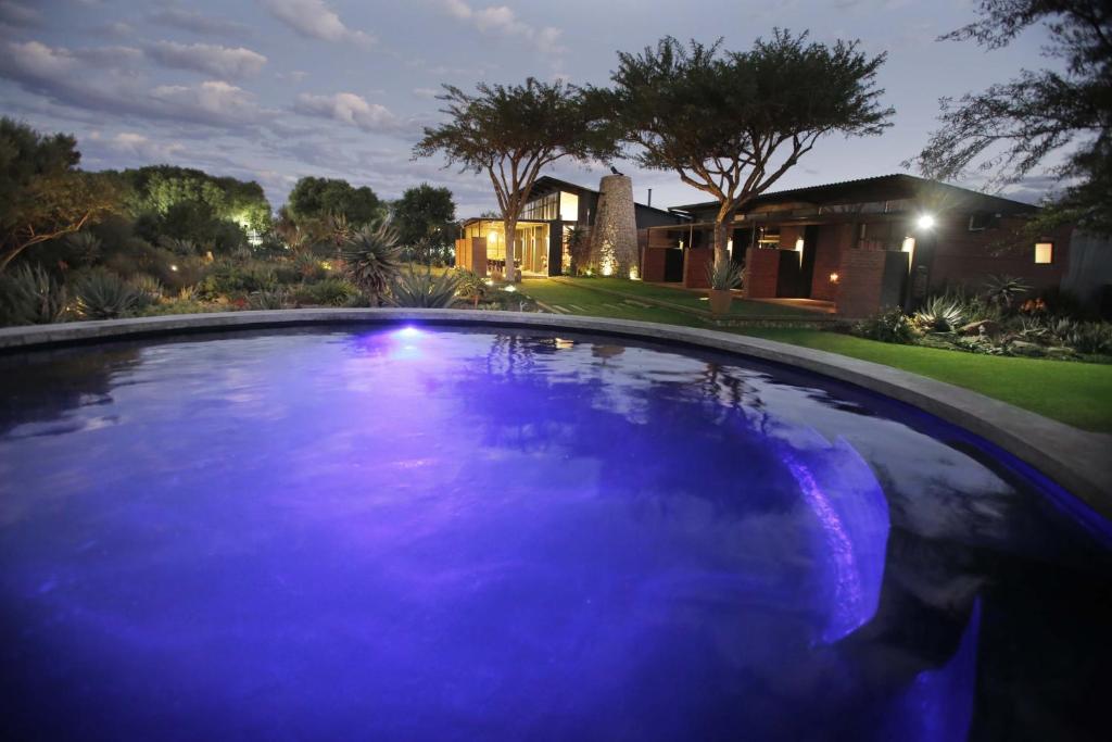 ein Schwimmbad vor einem Haus in der Nacht in der Unterkunft Liedjiesbos Urban Olive Farm in Bloemfontein
