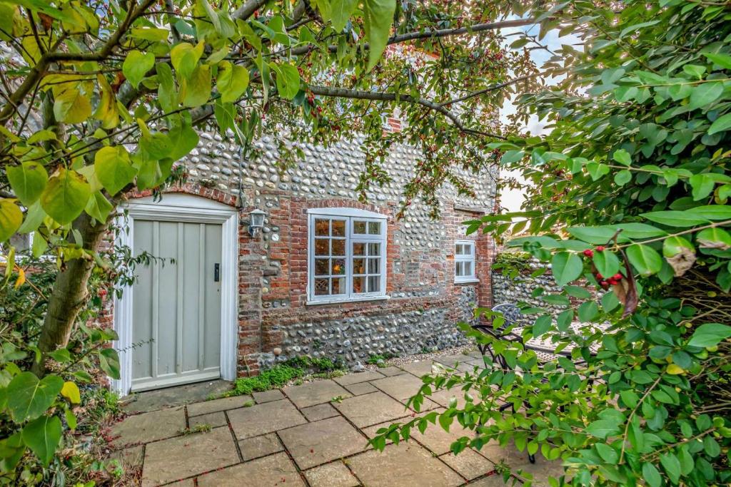 a brick house with a white door and a window at Bakers Cottage - Sidestrand in Sidestrand