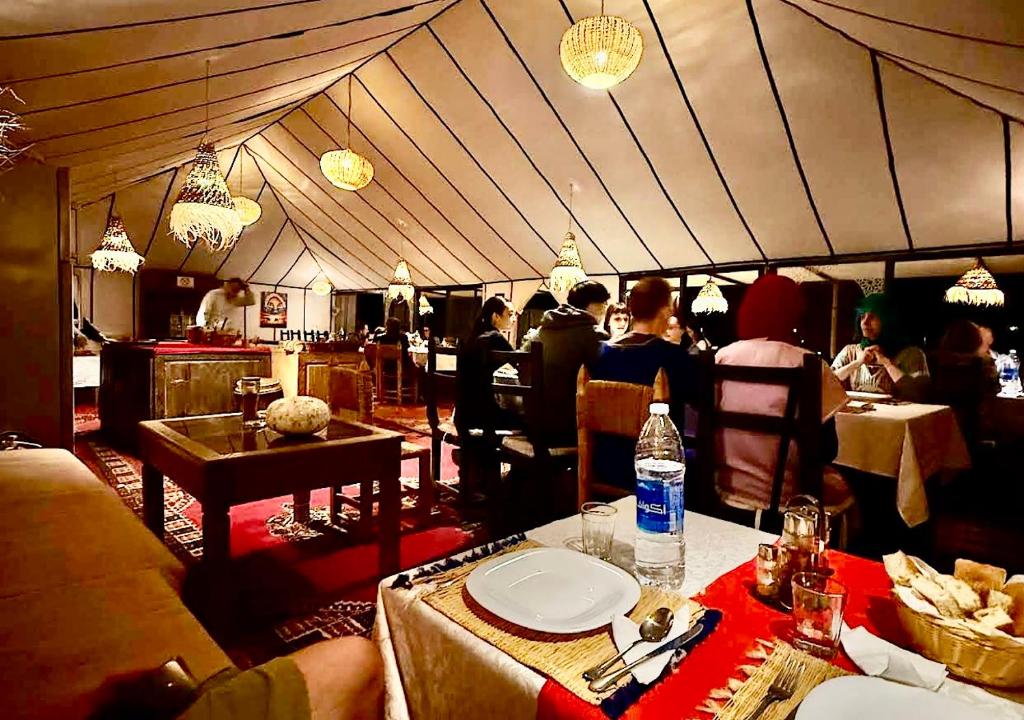 a dining room with people sitting in a tent at Treasure Desert Camp in Merzouga
