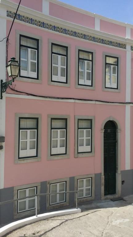 a pink building with windows and a door at Casa do Beco in Lisbon