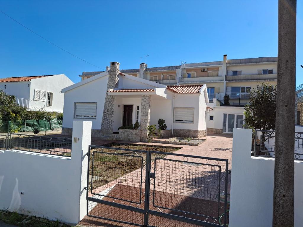 a white house with a gate in front of a building at Casa R in Sesimbra