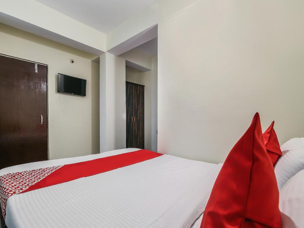 a bedroom with a bed with red pillows at Hotel O Lokenath in Jamshedpur
