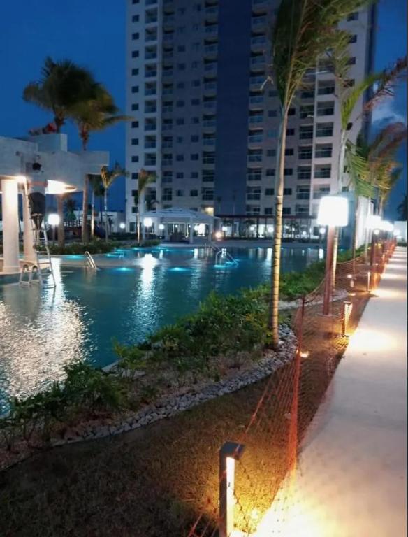 a swimming pool at night with palm trees and a building at Salinas Exclusive in Salinópolis