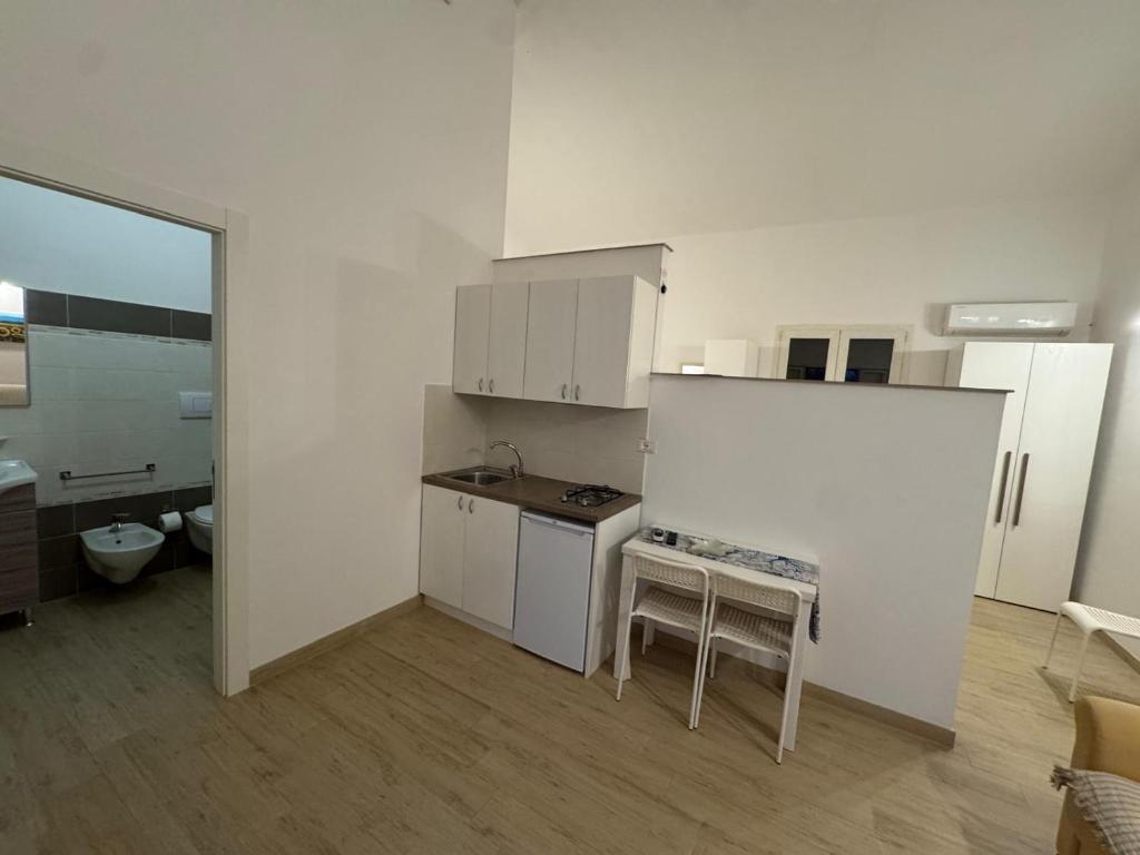 cocina con armarios blancos, mesa y taburete en Agriturismo Masseria Pallanzano, en Otranto