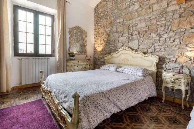 Un dormitorio con una pared de piedra y una cama en Lorenzo Magnifico Typical Home Heart of Florence, en Florencia