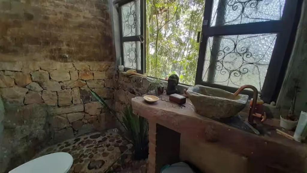 a stone bathroom with a sink and a window at Ayur nidhi Eco Hostel in Petrópolis