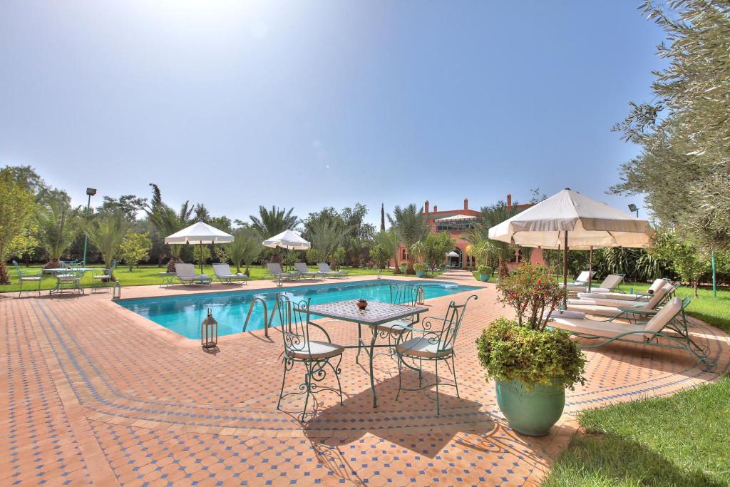 un patio con mesa y sillas junto a una piscina en Villa Dar Mya Palmiers, en Marrakech