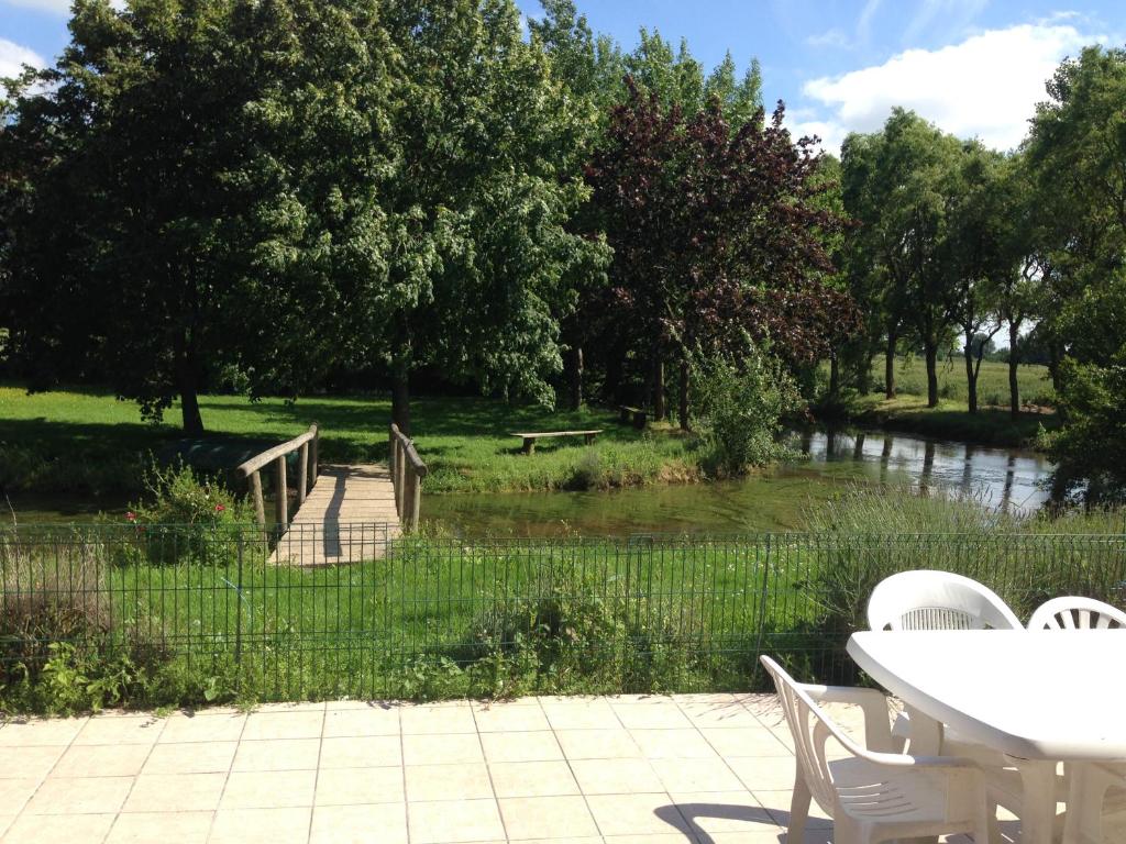 une table et des chaises à côté d'une rivière avec un pont dans l'établissement Gite Campagne-Bergues, à Socx