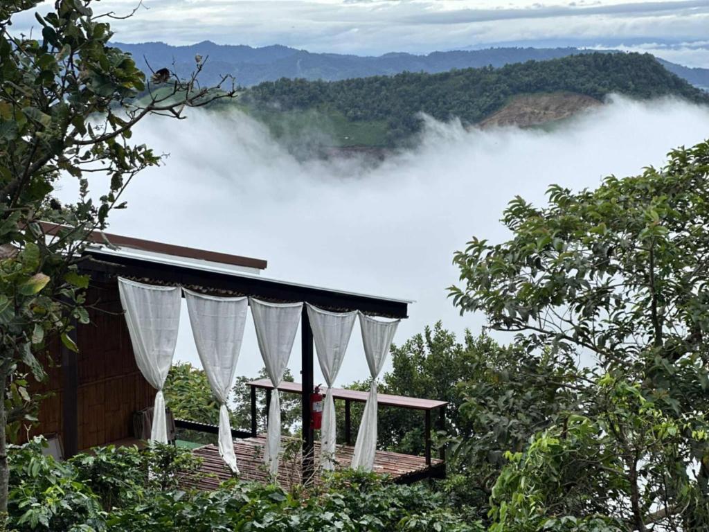 a house with white curtains and a view of the mountains at บ้านสวนเอลเลน in Ban Huai Khai