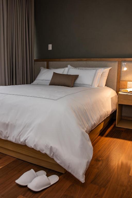 a large bed with white sheets and shoes on the floor at S22 Hotel & Suites in San Luis Potosí