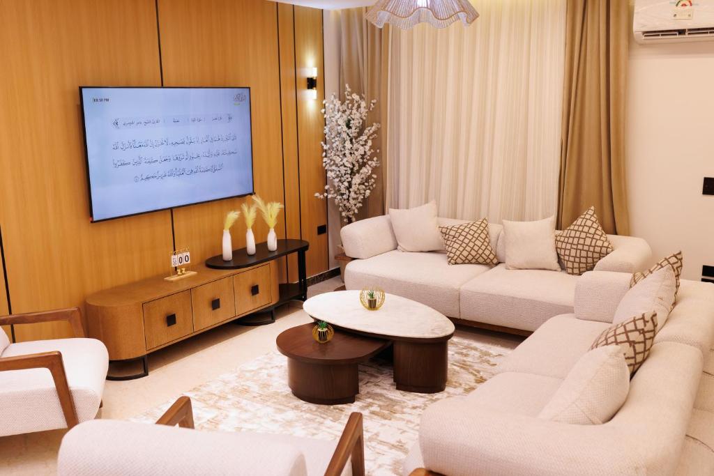 ein Wohnzimmer mit weißen Möbeln und einem Flachbild-TV in der Unterkunft شقة فندقية فاخرة شارع جيهان الرئيسي بجوار النيل و جامعه المنصوره in Mansoura