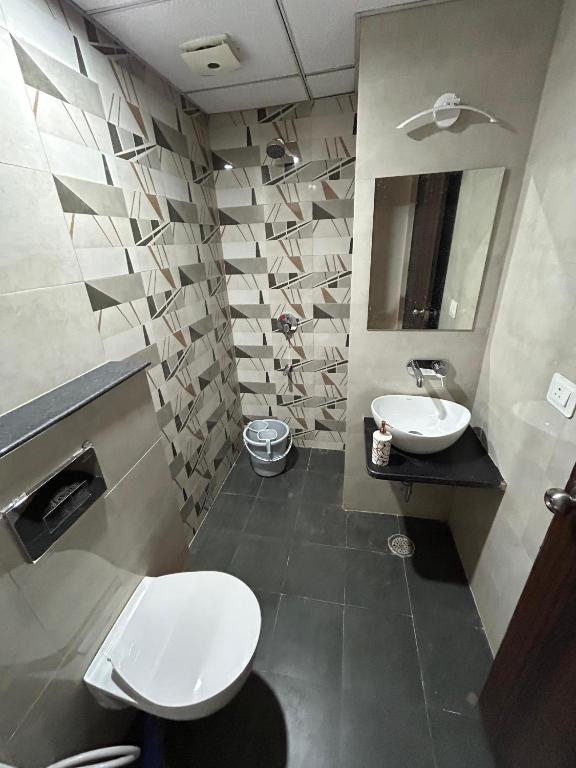 Un baño con inodoro, lavabo y espejo. en SR Elite Stays, en Jaipur