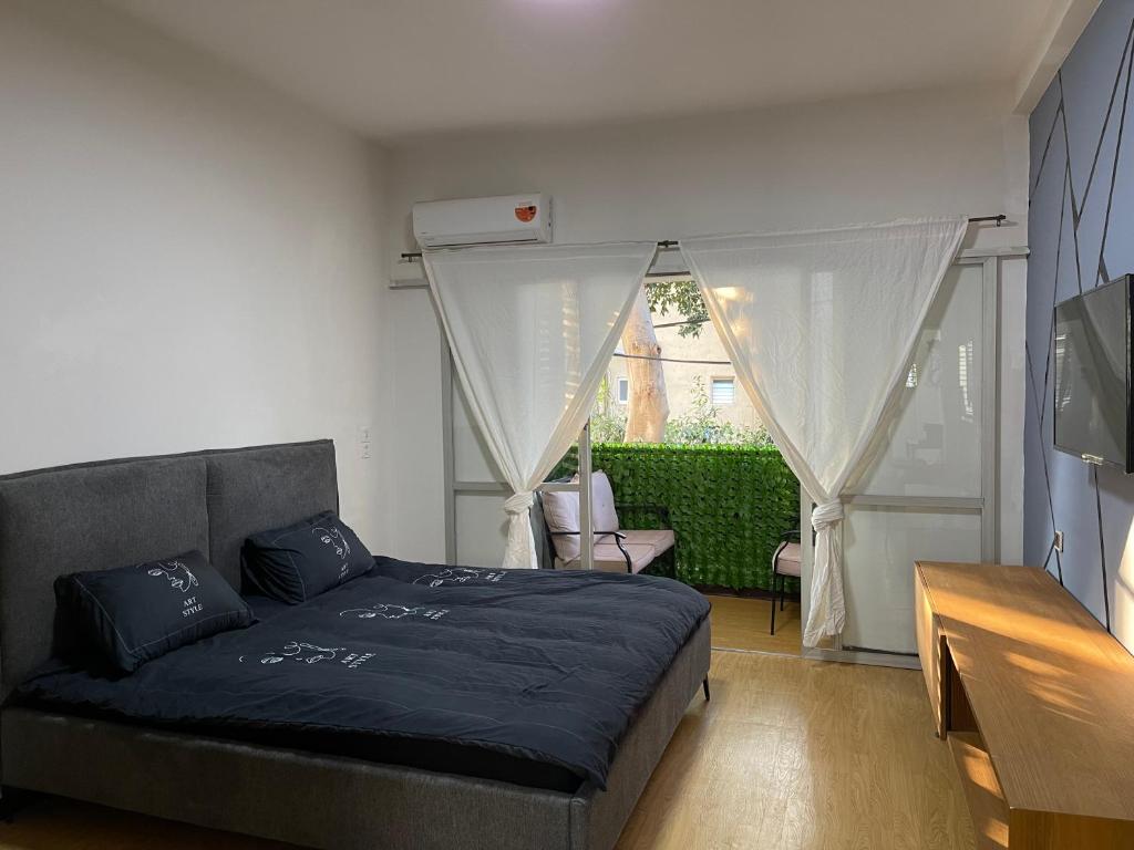 a bedroom with a bed in a room with a window at Bat Galim BEACH- Mirror apartment in Haifa